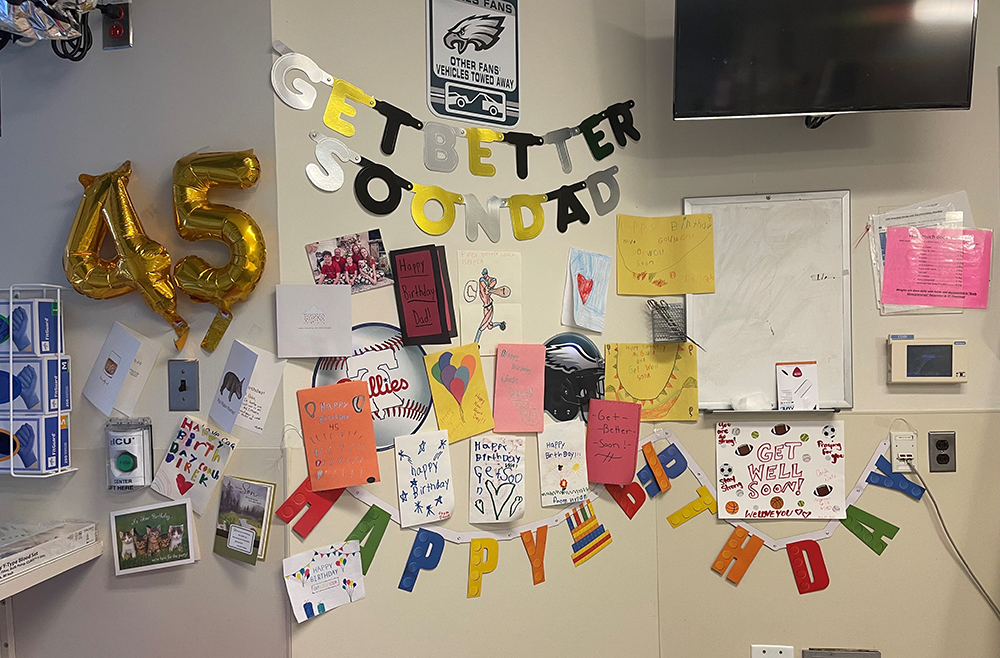 A wall covered in birthday decorations, including a gold 45 balloon, Happy Birthday and Get Better Soon Dad banners, and about 20 birthday cards and signs.